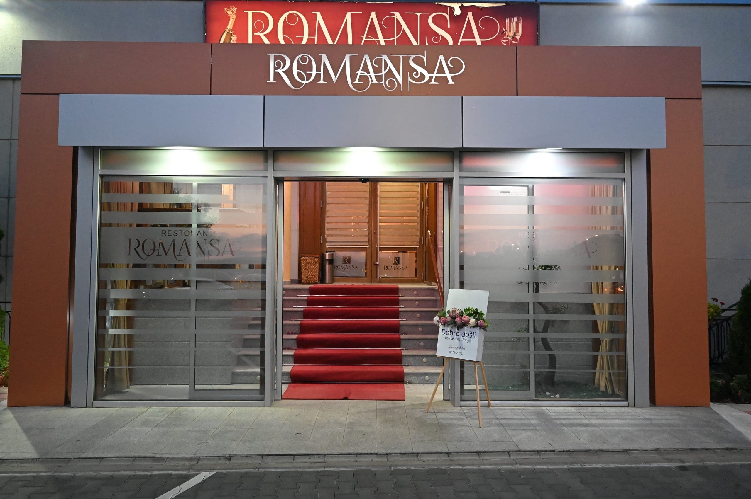 Ulaz u restoran Romansa uveče, sa crvenim tepihom