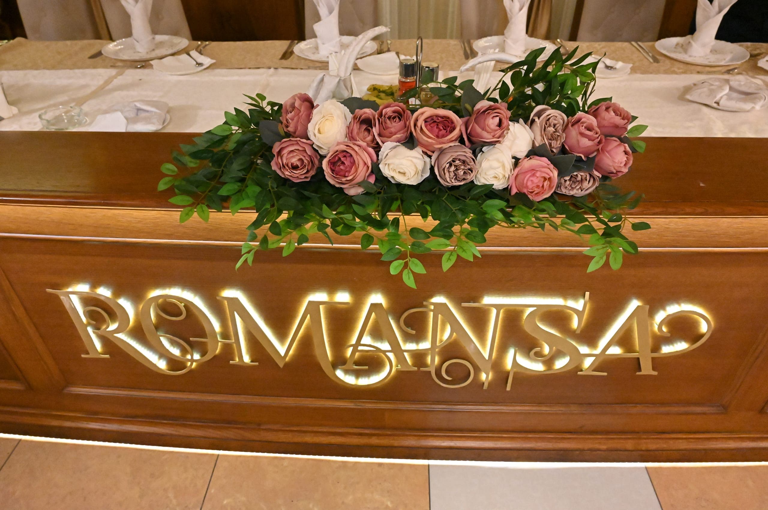 Detalj drvenog natpisa Romansa ukrašenog ružama na stolu za mladence