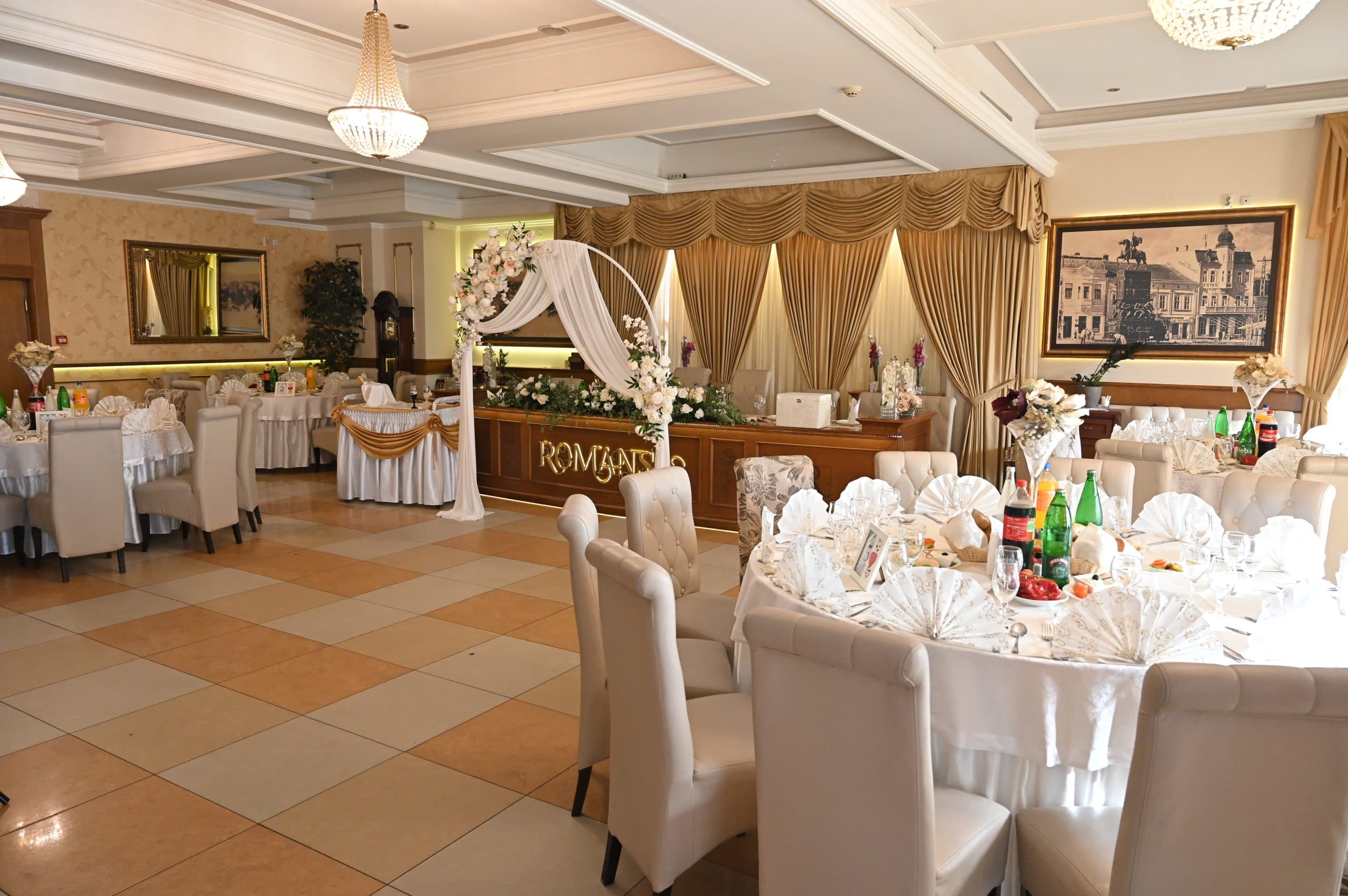 Elegantno uređena sala restorana Romansa sa lusterima i svečano postavljenim stolovima